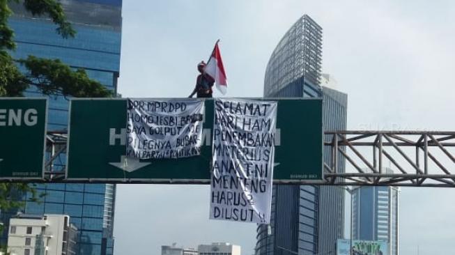 Lagi, Agustinus Nekat Manjat, Kali ini Papan Penunjuk Jalan Sudirman