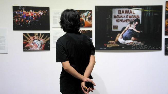 Pengunjung melihat pameran foto "Scapegoating The Other in Southeast Asia" di Galeri Salihara, Jakarta Selatan, Jumat (7/12).[Suara.com/Fakhri Hermansyah]