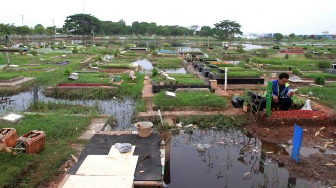 Warga berziarah ke makam keluarga di pemakaman yang terendam banjir di daerah Semper, Jakarta Utara, Sabtu (8/12). (Suara.com/Fakhri Hermansyah)