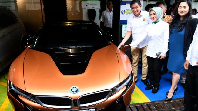 Menteri ESDM Ignasius Jonan (kiri) didampingi Dirut Pertamina Nicke Widyawati (tengah) dan VP of Corporate Communication BMW Group Indonesia Jodie O'tania (kanan) melakukan pengisian mobil listrik BMW i8 Roadster saat peluncuran Green Energy Station (GES) Pertamina di Jakarta, Senin (10/12/2018). GES Pertamina merupakan sarana pengisian daya untuk kendaraan listrik yang akan menjadi kendaraan di masa depan. [ANTARA FOTO/Akbar Nugroho Gumay]