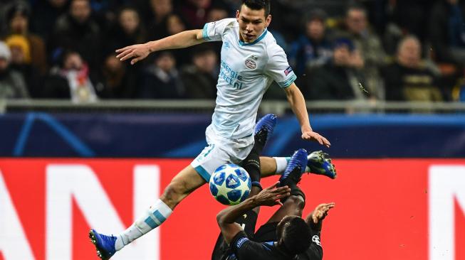 Gelandang Inter Milan Kwadwo Asamoah jatuh saat menghadang pemain depan PSV Eindhoven, Hirving Lozano selama pertandingan grup B Liga Champions di Stadion San Siro, Milan, Italia, Rabu (12/12). [Miguel MEDINA / AFP]