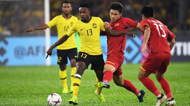 Pemain Malaysia Mohamadou Sumareh mencoba melewati pemain Vietnam, Doan Van Hau pada leg pertama final Piala AFF 2018 di Stadion Nasional Bukit Jalil, Malaysia (11/12/2018) (AFP)