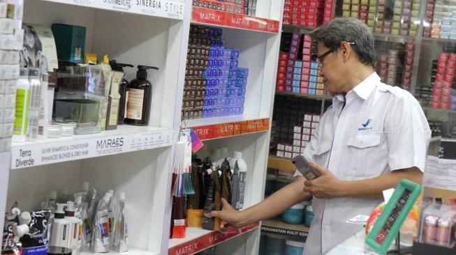 Petugas  gabungan Badan Pengawas Obat dan Makanan (BPOM) bersama Satpol  PP Jakarta  memeriksa kosmetik impor saat inspeksi mendadak di pertokoan Pasar Baru, Jakarta Pusat, Rabu (12/12). [Suara.com/Fakhri Hermansyah]