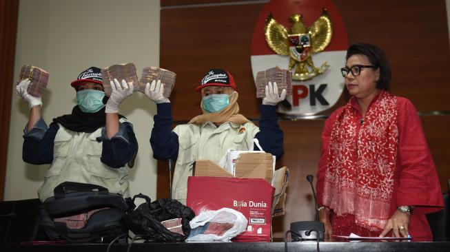 Wakil Ketua KPK Basaria Pandjaitan (kanan) menyaksikan petugas menunjukkan barang bukti uang yang diamankan dari operasi tangkap tangan (OTT) di Cianjur saat konferensi pers di Jakarta, Rabu (12/12). [ANTARA FOTO/Akbar Nugroho Gumay]