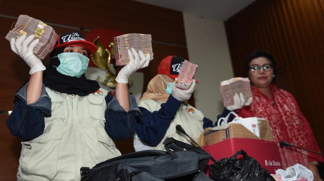 Wakil Ketua KPK Basaria Pandjaitan (kanan) menyaksikan petugas menunjukkan barang bukti uang yang diamankan dari operasi tangkap tangan (OTT) di Cianjur saat konferensi pers di Jakarta, Rabu (12/12). [ANTARA FOTO/Akbar Nugroho Gumay]