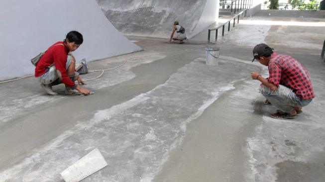 Sejumlah pekerja menyelesaikan proses pembuatan arena papan seluncur atau skate park dan lintasan sepeda BMX di kolong flyover Slipi, Jakarta Barat, Jumat (14/12). [Suara.com/Fakhri Hermansyah]