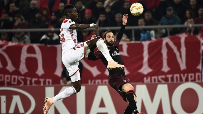 Gelandang Olympiakos Piraeus Pape Abou Cisse bersaing memperebutkan bola dengan Gonzalo Higuain Milan selama pertandingan sepak bola Liga Europa grup F antara Olympiakos melawan AC Milan di Stadion Karaiskaki, Piraeus, Yunani, Jumat (14/12). [ARIS MESSINIS / AFP]