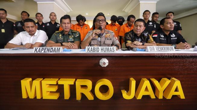 Kabid humas Polda Metro Jaya Kombes Pol Argo Yuwono bersama dengan Kapendam Jaya Kolonel Inf Kristomei Sianturi dan Direskrimum Kombes Pol Roycke Harry Langie memberikan keterangan saat rilis pengungkapan kasus pengeroyokan anggota TNI di Polda Metro Jaya, Jakarta, Jumat (14/12).[Suara.com/Muhaimin A Untung]