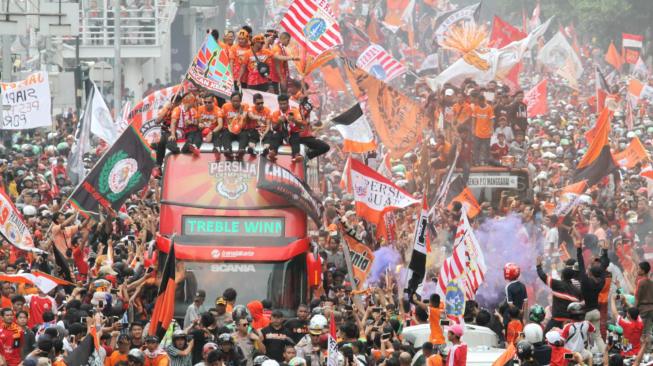 Pendukung Persija Jakarta The Jak mania menyambut iring-iringan pemain beserta  official di Thamrin, Jakarta Pusat, Sabtu (15/12).  [Suara.com/Fakhri Hermansyah]