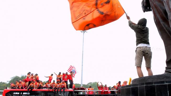 Pendukung Persija Jakarta The Jak mania menyambut iring-iringan pemain beserta  official di Thamrin, Jakarta Pusat, Sabtu (15/12).  [Suara.com/Fakhri Hermansyah]