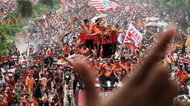 Pendukung Persija Jakarta The Jak mania menyambut iring-iringan pemain beserta  official di Thamrin, Jakarta Pusat, Sabtu (15/12).  [Suara.com/Fakhri Hermansyah]