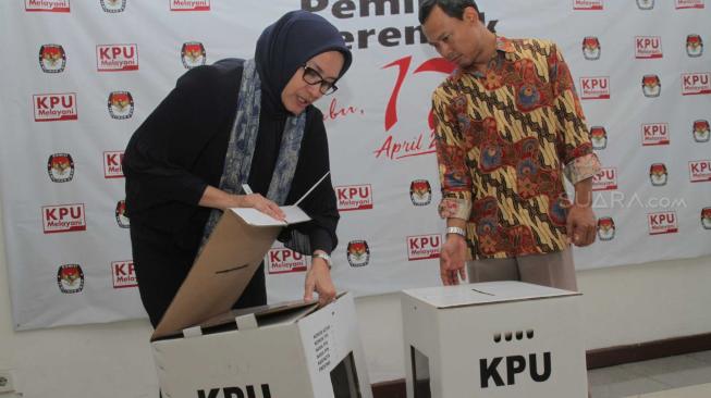 Komisioner KPU RI, Evi Novida Ginting Manik (kiri) dan Pramono Ubaid Tanthowi (kanan) menunjukan kotak suara bermaterial karton kedap air dan transparan di Kantor KPU Pusat, di Jakarta, Jumat (14/12). [Suara.com/Fakhri Hermansyah]