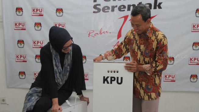 Komisioner KPU RI, Evi Novida Ginting Manik (kiri) dan Pramono Ubaid Tanthowi (kanan) menunjukan kotak suara bermaterial karton kedap air dan transparan di Kantor KPU Pusat, di Jakarta, Jumat (14/12). [Suara.com/Fakhri Hermansyah]