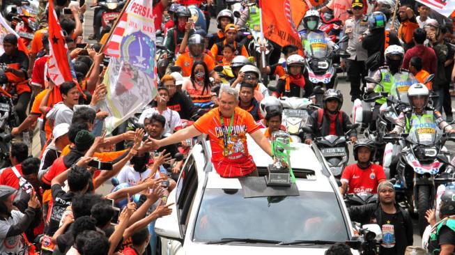 Pendukung Persija Jakarta The Jak mania menyambut iring-iringan pemain beserta  official di Thamrin, Jakarta Pusat, Sabtu (15/12).  [Suara.com/Fakhri Hermansyah]