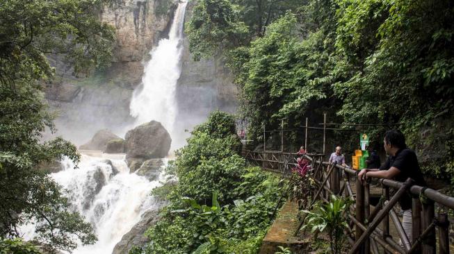 Pengunjung menikmati keindahan air terjun di kawasan wisata alam Geopark Curug Cimarinjung, Ciemas, Kabupaten Sukabumi, Jawa Barat, Minggu (16/12/2018). ANTARA FOTO/Nurul Ramadhan