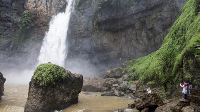 Pengunjung menikmati keindahan air terjun di kawasan wisata alam Geopark Curug Cimarinjung, Ciemas, Kabupaten Sukabumi, Jawa Barat, Minggu (16/12/2018). ANTARA FOTO/Nurul Ramadhan