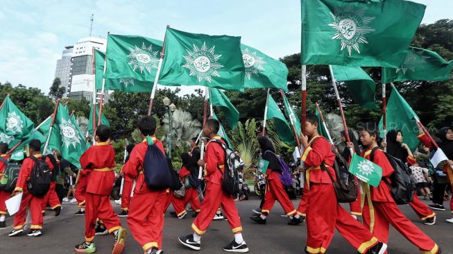 Sejumlah peserta mengikuti jalan santai keluarga besar Muhammadiyah DKI jakarta di Silang Barat Daya Monas, Jakarta, Minggu (16/12). [Suara.com/Muhaimin A Untung]