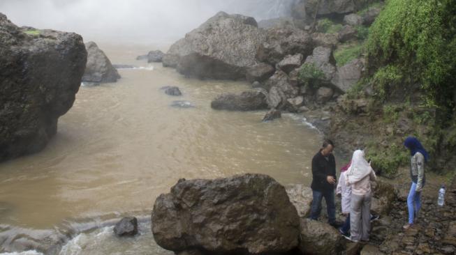 Pengunjung menikmati keindahan air terjun di kawasan wisata alam Geopark Curug Cimarinjung, Ciemas, Kabupaten Sukabumi, Jawa Barat, Minggu (16/12/2018). ANTARA FOTO/Nurul Ramadhan