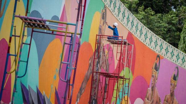 Pekerja menyelesaikan gambar mural bertema tokoh pewayangan di proyek Overpass Manahan, Solo, Jawa Tengah, Minggu (16/12). ANTARA FOTO/Mohammad Ayudha