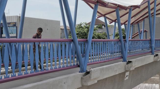 Pekerja membersihkan di Jembatan Penyeberangan Orang (JPO) bernuansa Betawi di Jalan Tubagus Angke, Jakarta Utara, Senin (17/12). [Suara com/Fakhri Hermansyah]