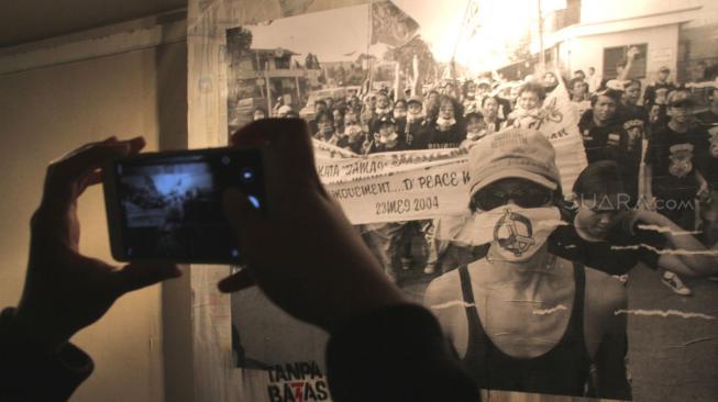 Pengunjung melintas dekat karya dalam acara Pameran Foto "Tanpa Batas" karya Tjandra Moh Amin di Galeri Cipta III, Taman Ismail Marzuki, Jakarta, Selasa (18/12). [Suara.com/Fakhri Hermansyah]