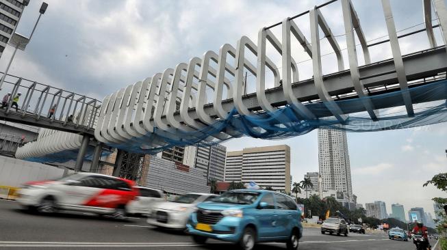 Pekerja melakukan pengerjaan proyek revitalisasi Jembatan Penyeberangan Orang (JPO) Bundaran Senayan di Jakarta, Selasa (18/12). [Suara.com/Muhaimin A Untung]