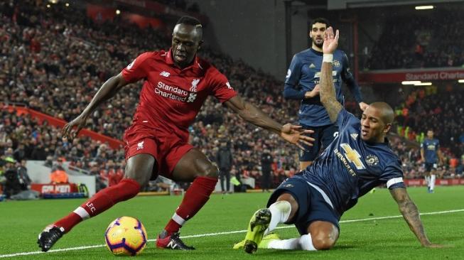 Pemain Liverpool Sadio Mane berduel dengan pemain Manchester United Ashley Young (kanan) dalam pertandingan yang berlangsung di Anfield pada Minggu (16/12/2018) [AFP]