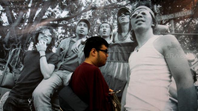 Pengunjung melintas dekat karya dalam acara Pameran Foto "Tanpa Batas" karya Tjandra Moh Amin di Galeri Cipta III, Taman Ismail Marzuki, Jakarta, Selasa (18/12). [Suara.com/Fakhri Hermansyah]