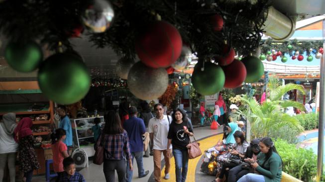 Pejalan kaki melintasi Terowongan Penyeberangan Orang (TPO) Kota Tua yang dihiasi pernak-pernik Natal, Jakarta Barat, Rabu, (19/12). [Suara com/Fakhri Hermansyah]