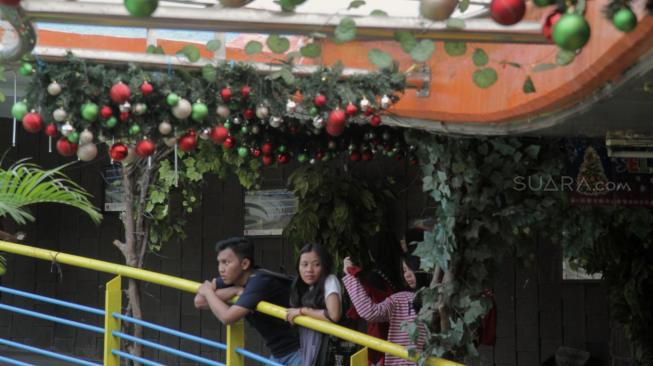 Pejalan kaki melintasi Terowongan Penyeberangan Orang (TPO) Kota Tua yang dihiasi pernak-pernik Natal, Jakarta Barat, Rabu, (19/12). [Suara com/Fakhri Hermansyah]