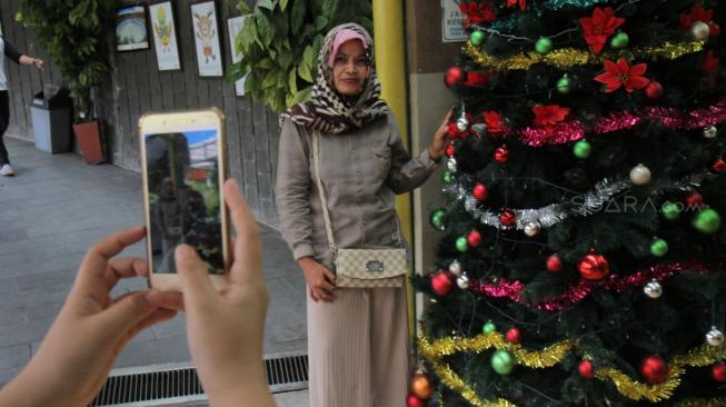 Pejalan kaki melintasi Terowongan Penyeberangan Orang (TPO) Kota Tua yang dihiasi pernak-pernik Natal, Jakarta Barat, Rabu, (19/12). [Suara com/Fakhri Hermansyah]