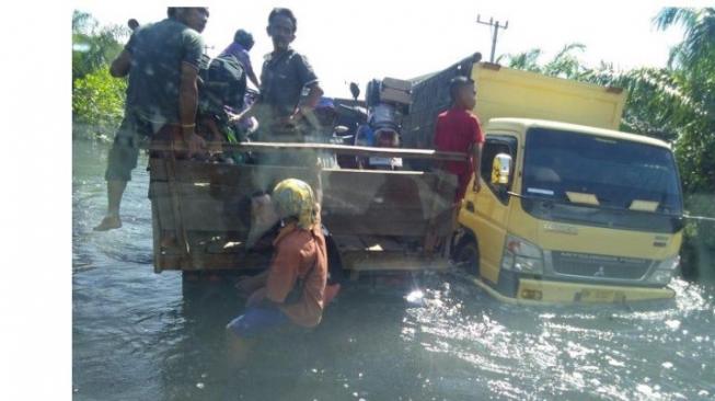 Suasana banjir di Pelalawan, ibu membonceng truk [Facebook: Reno Ibrahim].