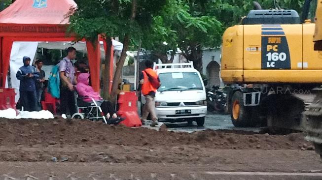 Berkursi Roda, Wali Kota Risma Basah-basahan Pantau Lokasi Jalan Ambles