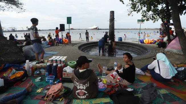 Pengunjung bermain di Pantai Langon, Ancol, Jakarta, Senin (25/12). [Suara.com/Muhaimin A Untung]