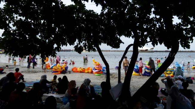 Pengunjung bermain di Pantai Langon, Ancol, Jakarta, Senin (25/12). [Suara.com/Muhaimin A Untung]