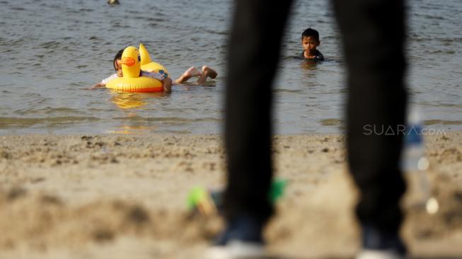 Pengunjung bermain di Pantai Langon, Ancol, Jakarta, Senin (25/12). [Suara.com/Muhaimin A Untung]