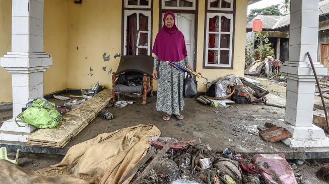 Warga berdiri di depan rumahnya yang hancur diterjang gelombang tsunami Selat Sunda di Kecamatan Sumur, Pandeglang, Banten, Selasa (25/12). [ANTARA FOTO/Muhammad Adimaja]