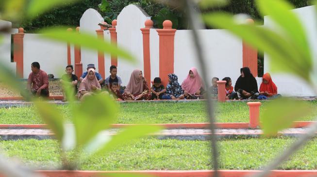 Sejumlah umat muslim membaca Surat Yasin dan doa bersama saat berziarah ke kuburan massal korban gempa dan gelombang tsunami di Desa Suak Indrapuri, Johan Pahlawan, Aceh Barat, Aceh, Rabu (26/12). [ANTARA FOTO/Syifa Yulinnas]