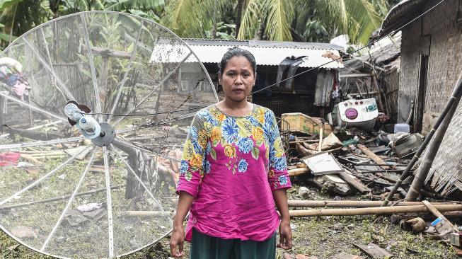 Warga berdiri di depan rumahnya yang hancur diterjang gelombang tsunami Selat Sunda di Kecamatan Sumur, Pandeglang, Banten, Selasa (25/12). [ANTARA FOTO/Muhammad Adimaja]