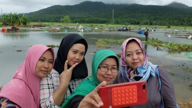 Solihat dan tiga rekannya selfie di dekat lokasi bencana tsunami Selat Sunda, di daerah Banten. [The Guardian/Jamie Fullerton]