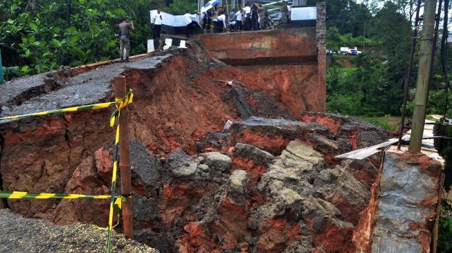 Sejumlah warga melihat jalan tepi jembatan yang ambles di Kampung Leuwi Jaksi, Cimarga, Lebak, Banten, Rabu (26/12). [ANTARA FOTO/Muhammad Bagus Khoirunas]