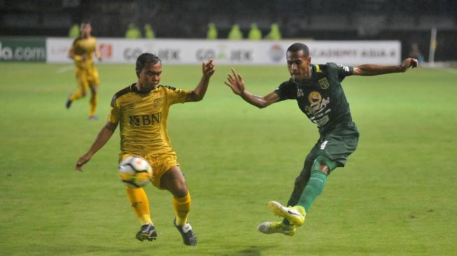 Bek Persebaya Surabaya, Ruben Sanadi (kanan) melepaskan tendangan yang coba dihadang pemain Bhayangkara FC Muhammad Fatchu Rochman dalam lanjutan Liga 1 2018 di Stadion Gelora Bung Tomo (GBT) Surabaya, Jawa Timur, Senin (26/11/2018). [Antara/M Risyal Hidayat]