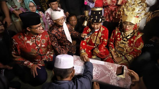 Gubernur DKI jakarta Anies Baswedan bersama Aa Gym menjadi saksi saat pasangan pengantin mengikuti nikah massal di Thamrin Park ride, Jakarta, Senin (31/12). [Suara.com/Muhaimin A Untung]