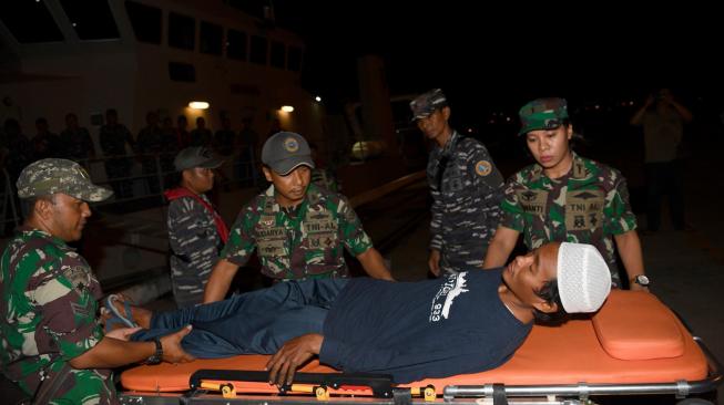 Prajurit TNI AL membawa korban selamat tsunami Selat Sunda, Ari Agus Arman Harianto usai turun dari KRI Rigel 933 di Dermaga Pelabuhan Indah Kiat, Cilegon, Banten, Minggu (30/12/2018). [ANTARA FOTO/Sigid Kurniawan]
