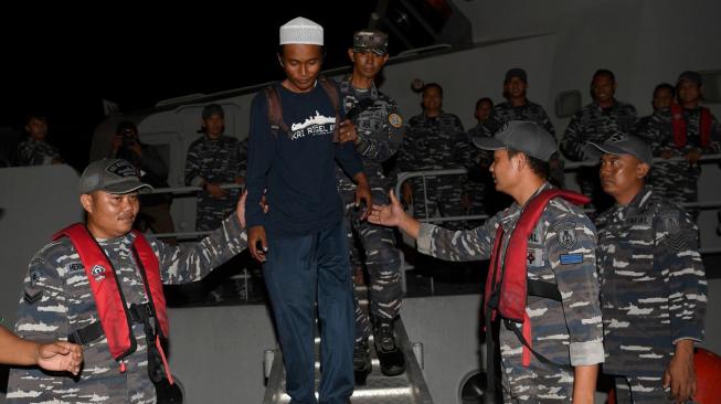 Korban selamat tsunami Selat Sunda, Ari Agus Arman Harianto (kedua kiri) turun dari KRI Rigel 933 di Dermaga Pelabuhan Indah Kiat, Cilegon, Banten, Minggu (30/12). [ANTARA FOTO/Sigid Kurniawan]