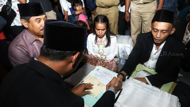 Pasangan pengantin mengikuti nikah massal di Thamrin Park ride, Jakarta, Senin (31/12). [Suara.com/Muhaimin A Untung]