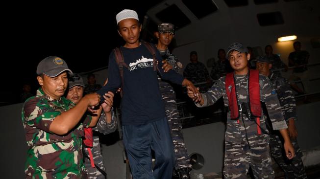 Korban selamat tsunami Selat Sunda, Ari Agus Arman Harianto (kedua kiri) turun dari KRI Rigel 933 di Dermaga Pelabuhan Indah Kiat, Cilegon, Banten, Minggu (30/12). [ANTARA FOTO/Sigid Kurniawan]