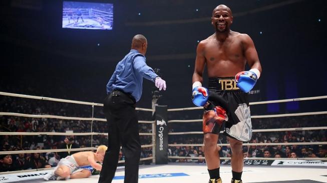 Petinju Amerika Serikat, Floyd Mayweather Jr. (kanan) tersenyum usai memukul jatuh atlet MMA asal Jepang, Tenshin Nasukawa (kiri), dalam laga ekshibisi tinju di Saitama, Jepang, Senin (31/12/2018). [AFP]