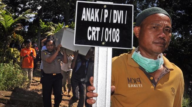 Warga membawa nisan diiringi Tim DVI (Disaster Victim Investigation) Polda Banten yang mengusung keranda jenazah saat Pemakaman Korban Tsunami tak teridentifikasi (tak dikenal) di TPU (Tempat Pemakaman Umum) Ninik-Aki di Cigadung, Pandeglang, Banten, Jumat (4/1). [ANTARA FOTO/Asep Fathulrahman]