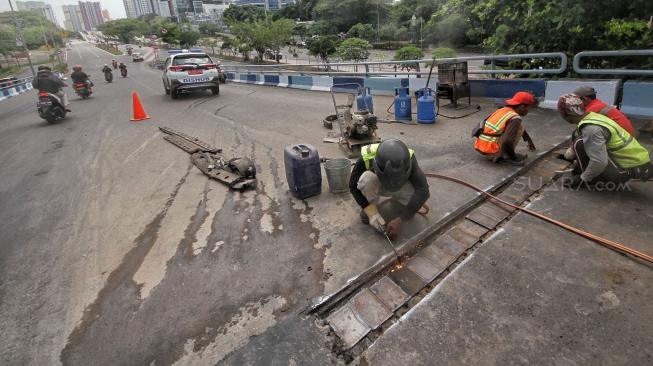 Petugas melakukan perbaikan Jembatan layangnyang renggang di Jalan Layang, Jalan Industri Raya, Kemayoran, Jakarta Pusat, Minggu (6/1). [Suara.com/Muhaimin A Untung] 